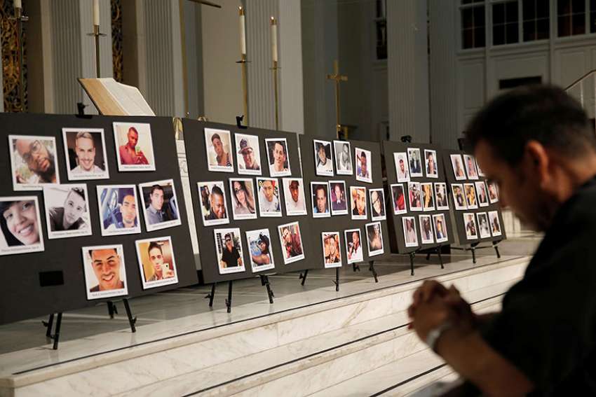 A man prays in front of photographs of victims of the Pulse nightclub shooting in Orlando June 15, 2016. The Diocese of Orlando held a prayer service on the tragedy’s anniversary at St. James Cathedral June 12.