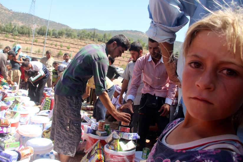 Members of the Yezidi religious minority who fled from violence in Mosul, Iraq, receive humanitarian aid Aug. 21 in Dohuk province, in the northern part of the country. Catholic relief agencies are trying raise more money for additional aid in the region.