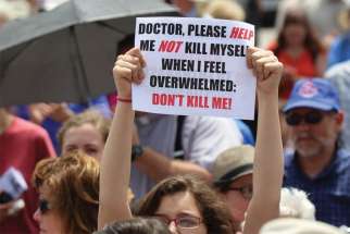  A woman holds a sign during a rally against physician-assisted suicide on Parliament Hill in Ottawa in this file photo.