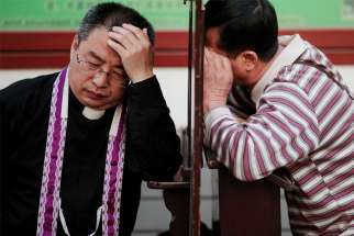 A file photo shows a priest hearing confession at the Cathedral of the Immaculate Conception in Beijing. The Chinese government said that in addition to meeting health requirements after the COVID-19 outbreak, priests must &quot;preach on patriotism&quot; as a condition for reopening their churches.