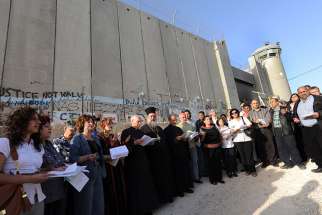Christian leaders pray in front of the Israeli separation wall.