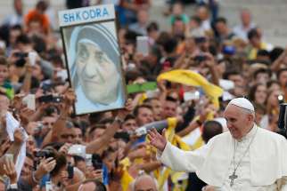 Pope Francis passes an image of Mother Teresa of Calcutta as he arrives to celebrate Mass in Mother Teresa Square in Tirana, Albania, in this Sept. 21, 2014 file photo. The Pope has approved a miracle attributed to the intercession of Blessed Teresa, paving the way for her canonization in 2016.