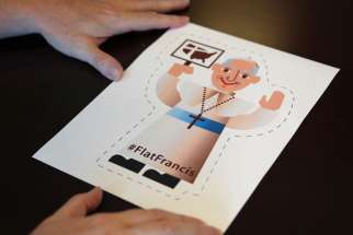 A Washington-based editor sizes up a cartoon image of Pope Francis June 24. Catholic Extension created &quot;Flat Francis&quot; to help people welcome the pontiff when he makes his U.S. visit in September. 