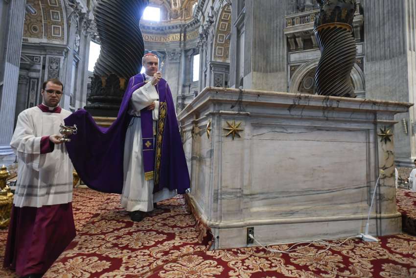 Cardinal Mauro Gambetti, archpriest of St. Peter&#039;s Basilica, uses holy water to bless the main altar in the basilica June 3, 2023, as part of an act of reparation after a man climbed on the altar naked.
