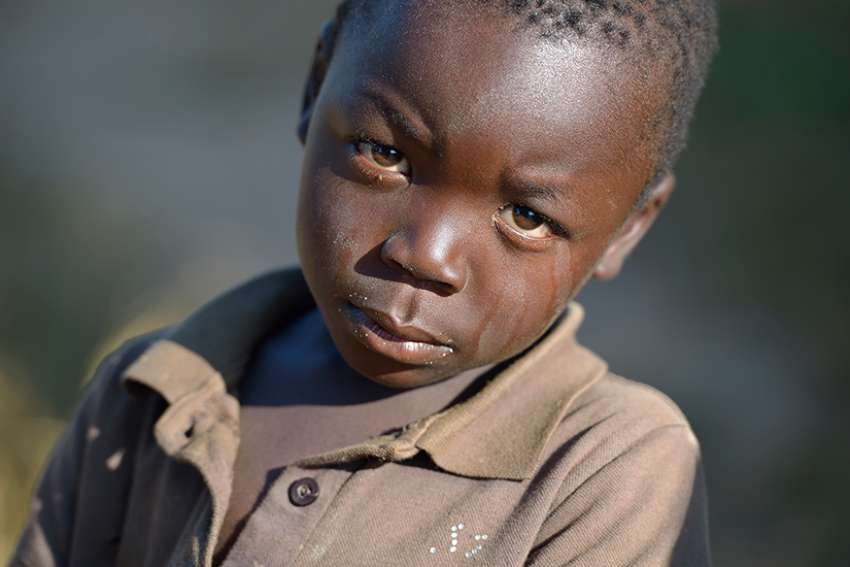  A boy looks into the lens of a camera in 2017 in Jombo, Malawi. With assistance from the AIDS program of the Church of Central Africa Presbyterian, a sexual and reproductive health club for children and youth operates in the village.