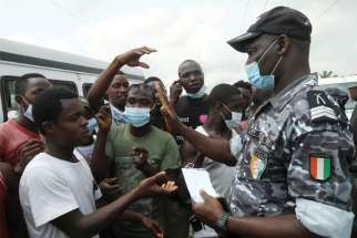 A road safety officer distributes masks during a COVID-19 awareness campaign in Abidjan, Ivory Coast, Jan. 19. While vaccines are rolling out in most developed nations, poor African nations are left wanting.