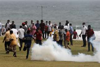 Supporters of the Sri Lankan ruling party run as riot police fire tear gas canisters during clashes with anti-government demonstrators in Colombo May 9, 2022.