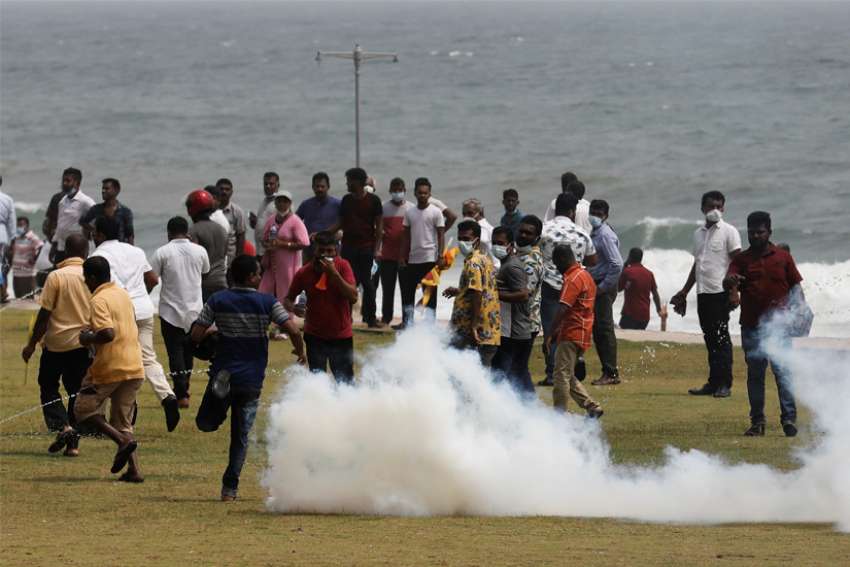Supporters of the Sri Lankan ruling party run as riot police fire tear gas canisters during clashes with anti-government demonstrators in Colombo May 9, 2022.