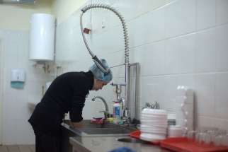 A woman known as Lesia washes dishes at Walnut House Nov. 21. She is a widow with two children who do not live with her.