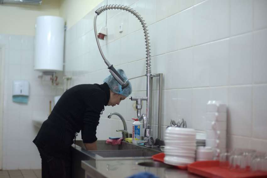 A woman known as Lesia washes dishes at Walnut House Nov. 21. She is a widow with two children who do not live with her.