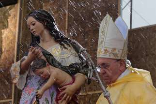 Rain falls as Pope Francis walks past a statue of Mary and the Christ child as he celebrates Mass adjacent to the airport in Tacloban, Philippines, Jan. 17.