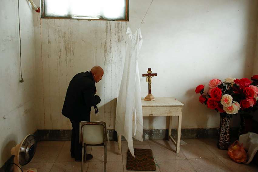 A retired bishop waits to hear confession from members of the congregation before Mass Dec. 23, 2016, at an unofficial Catholic church in Youtong village, Hebei Province, China.