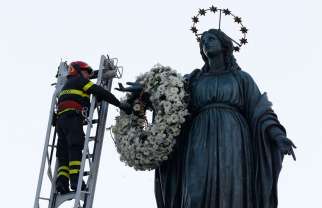 A firefighter places a wreath at the foot of a tall statue of Mary overlooking the Spanish Steps in Rome Dec. 8, the feast of the Immaculate Conception. Rome&#039;s firefighters have observed the tradition every year since 1857. 