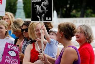 A pro-life demonstrator holds her child as activists gather outside the U.S. Supreme Court in Washington June 26 to celebrate the court decision striking down a Massachusetts law that mandated a buffer zone to keep pro-life demonstrators away from aborti on clinics.