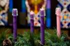 Two lit candles on an Advent wreath.