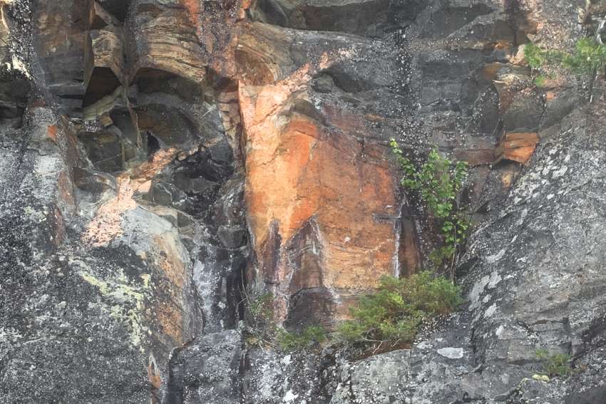 Students attending the Catholic Leadership Camp paddle past a rockface (pictured) rising from the water with a clear image of Christ on the Cross.