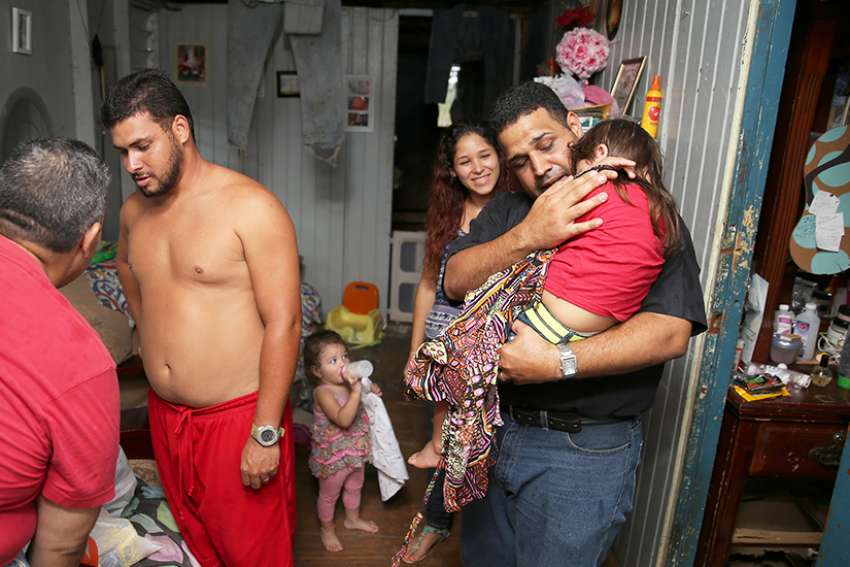 Father Carlos Francis Mendez, pastor of Immaculate Heart of Mary Church in Las Marias, Puerto Rico, comforts a girl at her home Oct. 24 in a remote area outside the town. Father Mendez, and parishioners distributed relief goods to their home and others in the poor area who were affected by Hurricane Maria. 