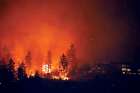 Fire burns near homes outside West Kelowna, B.C., Aug. 18, 2023. 