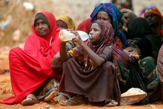 Internally displaced Somali women wait for relief food while a child drinks water April 9, 2017, at a distribution center in Baidoa, Somalia, after fleeing from drought stricken regions. The apostolic administrator of the Diocese of Mogadishu called on the world to &quot;pay attention to the plight of Somali people&quot; as they face critical food shortages because of a crippling drought. 