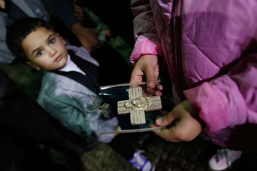 An Iraqi Christian refugee girl holds a souvenir of the Holy Family Dec. 12 as a boy looks on at a church in Hazmiyeh, near Beirut.