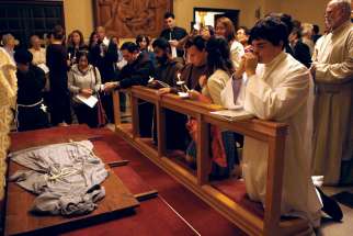 Followers of St. Francis pray over a habit Oct. 3 at the Franciscan Monastery of the Holy Land in Washington. Some Franciscans say Pope Francis has spurred a revival of Franciscan spirituality.