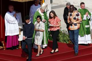 Young people walk away after presenting offertory gifts to Pope Francis during the opening Mass of the Synod of Bishops on young people, the faith and vocational discernment at the Vatican Oct 3. Pictured in red, Emilie Callan is one of Canada&#039;s youth observers to the synod.  