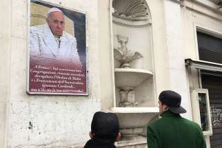 People look at a poster expressing criticism of Pope Francis in Rome Feb. 5. Several copies of the poster were placed in the centre of Rome but were quickly covered by city authorities. Several copies of the poster were placed in the center of Rome; some were quickly covered by city authorities.