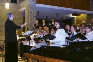 Staff Arts president and choir director Anne Bolger conducts the group’s version of “O Holy Night” at the Dec. 2 Christmas concert. Soloist Gilda De Marco Melo is at the right foreground.