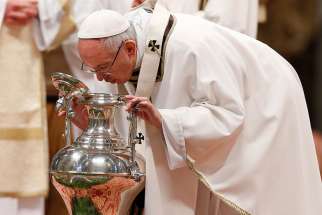 Pope Francis breathes over chrism oil, a gesture symbolizing the infusion of the Holy Spirit, during the Holy Thursday chrism Mass in St. Peter&#039;s Basilica at the Vatican April 13.