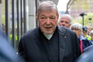 Australian Cardinal George Pell is surrounded by police as he leaves the Melbourne Magistrates Court in Australia, Oct. 6, 2017.
