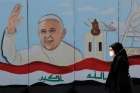 A woman walks past a mural of Pope Francis on a wall surrounding a church in Baghdad Feb. 22. Pope Francis plans to visit Iraq March 5-8.