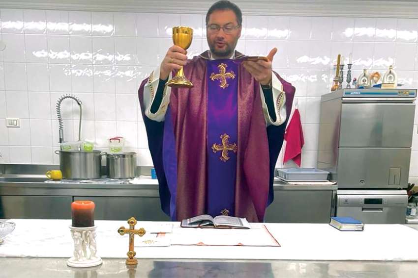 Archbishop Visvaldas Kulbokas, apostolic nuncio to Ukraine, elevates the Eucharist in the kitchen at the apostolic nunciature in Kyiv, Ukraine, in this recent photo. During the war, Kulbokas has been celebrating Mass in the kitchen because it’s a well-protected area.