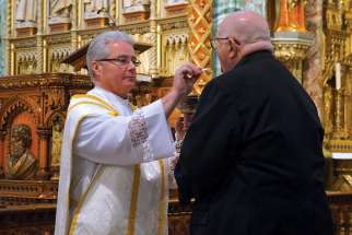 Msgr. Carl Reid giving communion after his ordination in 2013