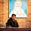 Toronto artist Viktor Mitic sits next to his 2008 painting of Jesus Christ, the first work of his Bullet Proof collection which is currently on display at The Peach Gallery in Toronto.