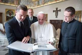 Actor Leonardo DiCaprio and Pope Francis look at a book during their meeting in the Apostolic Palace at the Vatican Jan. 28.