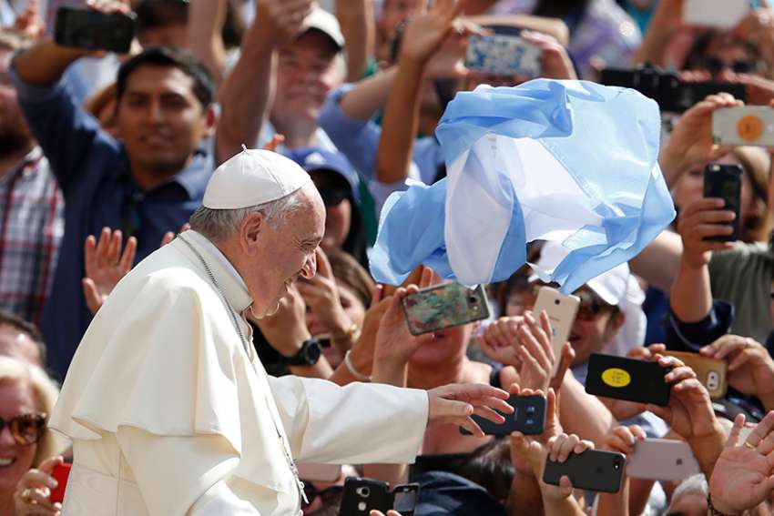 An item with the national colors of Argentina is thrown at Pope Francis as he greets the crowd during his general audience in St. Peter&#039;s Square at the Vatican June 13. The pope caught three objects of clothing or flags thrown at him within a span of a few seconds. 