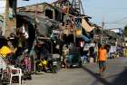 People walk past makeshift homes in early May at a shantytown outside Manila, Philippines.