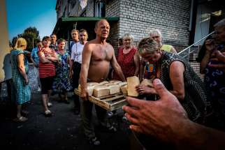 People living in shelters receive bread trays donated by members of the Donetsk People&#039;s Republic militias in Ilovaysk, Ukraine, in this Aug. 14, 2014 file photo, 