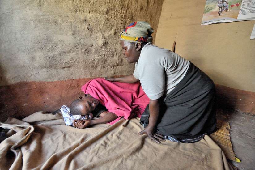Home-based care worker Olipa Mkandawire prays for a man living with AIDS in Matuli, Malawi, in this 2009 photo. Marking World AIDS Day Dec. 1, African bishops commended families and parishioners caring for people with HIV as the Year of Mercy approaches.