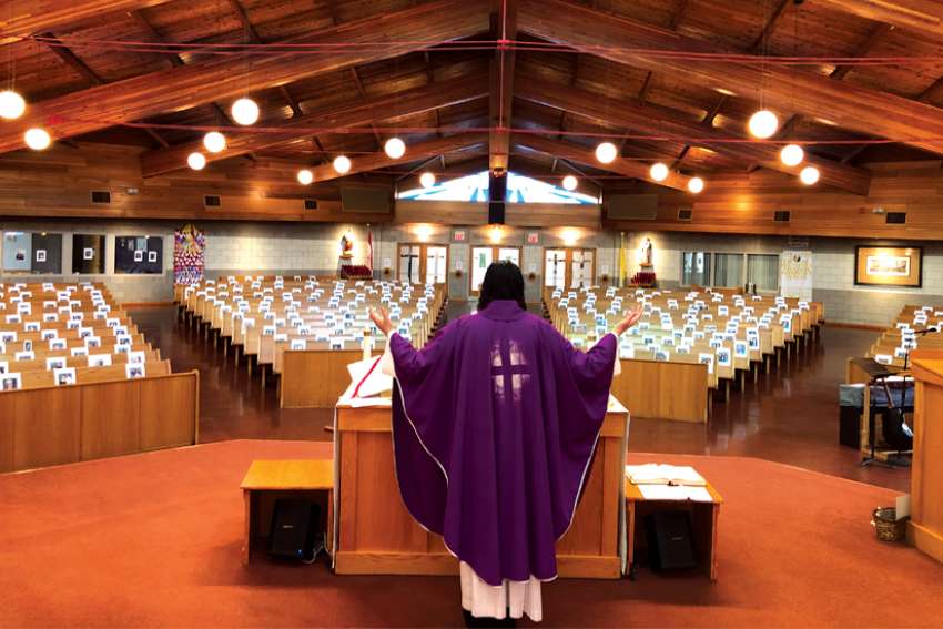 Fr. Rico Passero celebrates Mass at his parish in Grimsby, ON, with photos of his parishioners, which he has attached to the pews where each would normally sit on Sunday. 