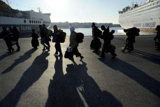 Refugees and migrants walk after disembarking from the passenger ferry Eleftherios Venizelos from the island of Lesbos at the port of Piraeus, near Athens, Greece, Dec 26, 2015.