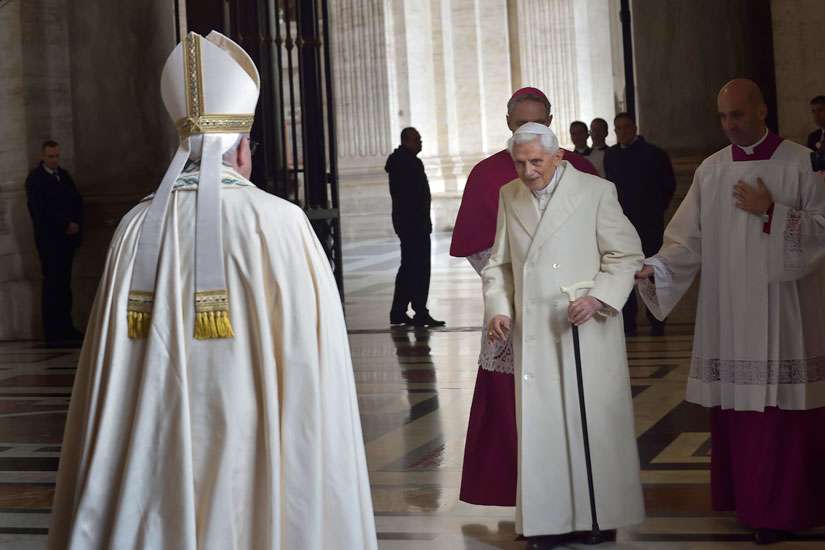 Retired Pope Benedict XVI prepares to greet Pope Francis during the opening of the Holy Door of St. Peter&#039;s Basilica at the Vatican in this Dec. 8, 2015, file photo. In a written interview, the retired pope commented on the theme of mercy. &quot;Mercy is what moves us toward God, while justice makes us tremble in his sight, Pope Benedict said.