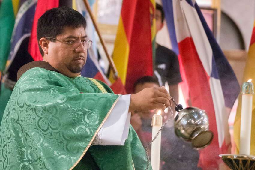 Father Urbano Vazquez swings a thurible over the altar at a Mass at the Shrine of the Sacred Heart in Washington.
