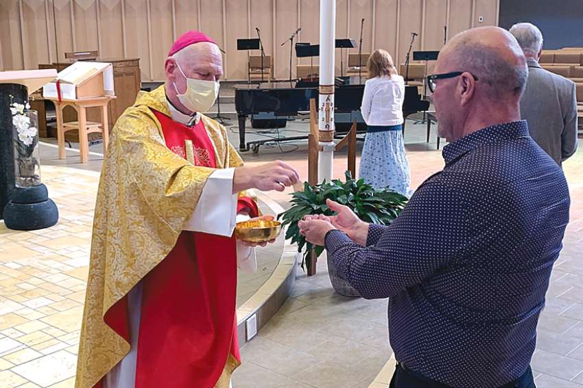 Bishop Mark Hagemoen distributes communion at the end of Mass May 24 at the Cathedral of the Holy Family in Saskatoon, the first weekend of phasing-in the resumption of public celebration of Mass in the diocese.