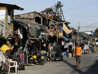 People walk past makeshift homes in early May at a shantytown outside Manila, Philippines.
