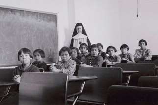 In this 1940 photo, a group of female students and a nun pose in a classroom at Cross Lake Indian Residential School in Manitoba. Blair Stonechild, a professor of indigenous studies at First Nations University of Canada, says the residential school periods in Canada was “spiritual abuse” and has deep roots.