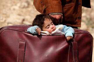  A child sleeps in a suitcase in Beit Sawa, Syria, March 15.