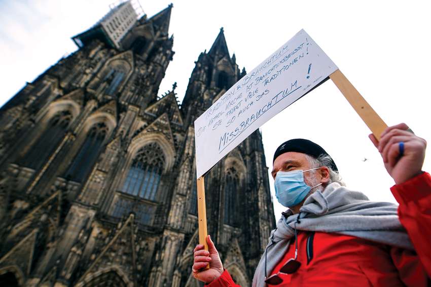 A demonstrator holds a placard during a protest in front of the Cologne Cathedral in Germany March 18, 2021. Lawyer Stephan Rixen, the state-appointed chairman of the commission to investigate abuse in the Archdiocese of Cologne, has quit.