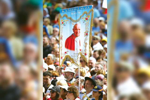 A pilgrim holds a banner showing St. John Paul II during an April 28 Mass of thanksgiving for the canonizations of new Sts. John Paul and John XXIII in St. Peter’s Square at the Vatican. Divine Mercy was the key to the late pope’s teaching.