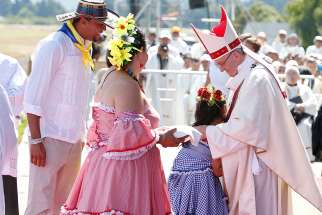 Pope Francis embraces a girl as he accepts offertory gifts during Mass at the Maquehue Airport near Temuco, Chile, Jan. 17.
